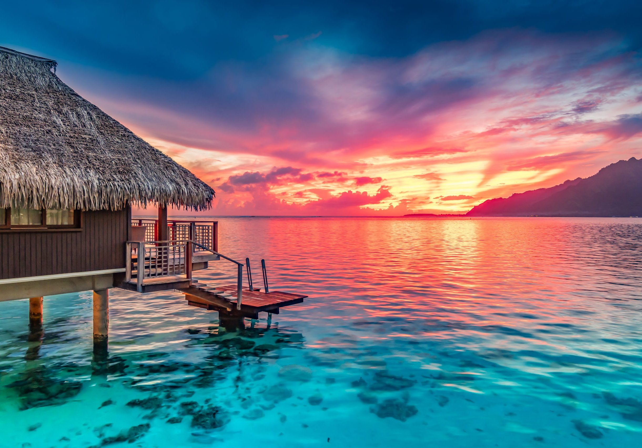 Stunning colorful sunset sky with clouds on the horizon of the South Pacific Ocean. Lagoon landscape in Moorea. Luxury travel.